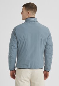 Herrenblauer gepolsterter Jacke mit höherem Kragen, ausgestattet mit einem schwarzen Innenfutter und elastischen Manschetten. Schlichtes Design, keine sichtbaren Muster.