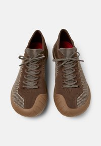 Brown athletic shoes with a textured surface, featuring tonal laces and a cushioned sole, viewed from above against a plain background.