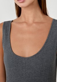 Top de tirantes gris acanalado con escote redondeado y tirantes anchos, que presenta una textura suave y un diseño ajustado.