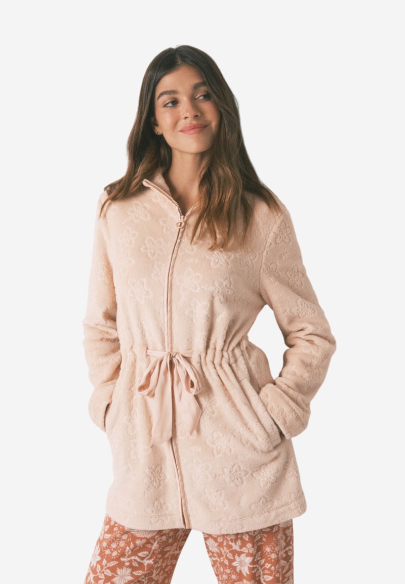 Fleece zip-up jakke i lys rosa med blomstermønster, snor i taljen og sidelommer. Blød tekstur og lange ærmer.