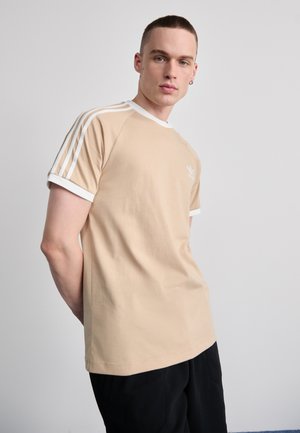 Beige cotton T-shirt with white accents, crew neck, and three white stripes on sleeves; features a small logo on the chest.