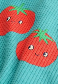 Gerippter Stoff mit roten Cartoon-Tomaten mit grünen Tops auf einem türkisfarbenen Hintergrund, verziert mit lächelnden Gesichtern und großen Augen.