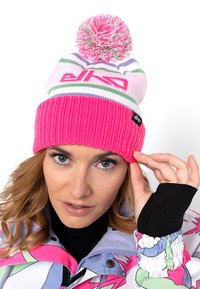 Roze gebreide beanie met een geribbelde structuur, witte en groene strepen, en een gekleurde pompon bovenop. Merkenlabel zichtbaar aan de zijkant.