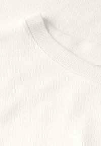 Tessuto di cotone bianco con una trama a coste e un collo a giro, con cuciture morbide e uniformi e cuciture minime visibili.