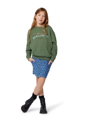 Sweatshirt en coton vert avec le texte "AMOUR", associé à une jupe en denim à imprimé léopard bleu. Des bottines noires viennent compléter la tenue.