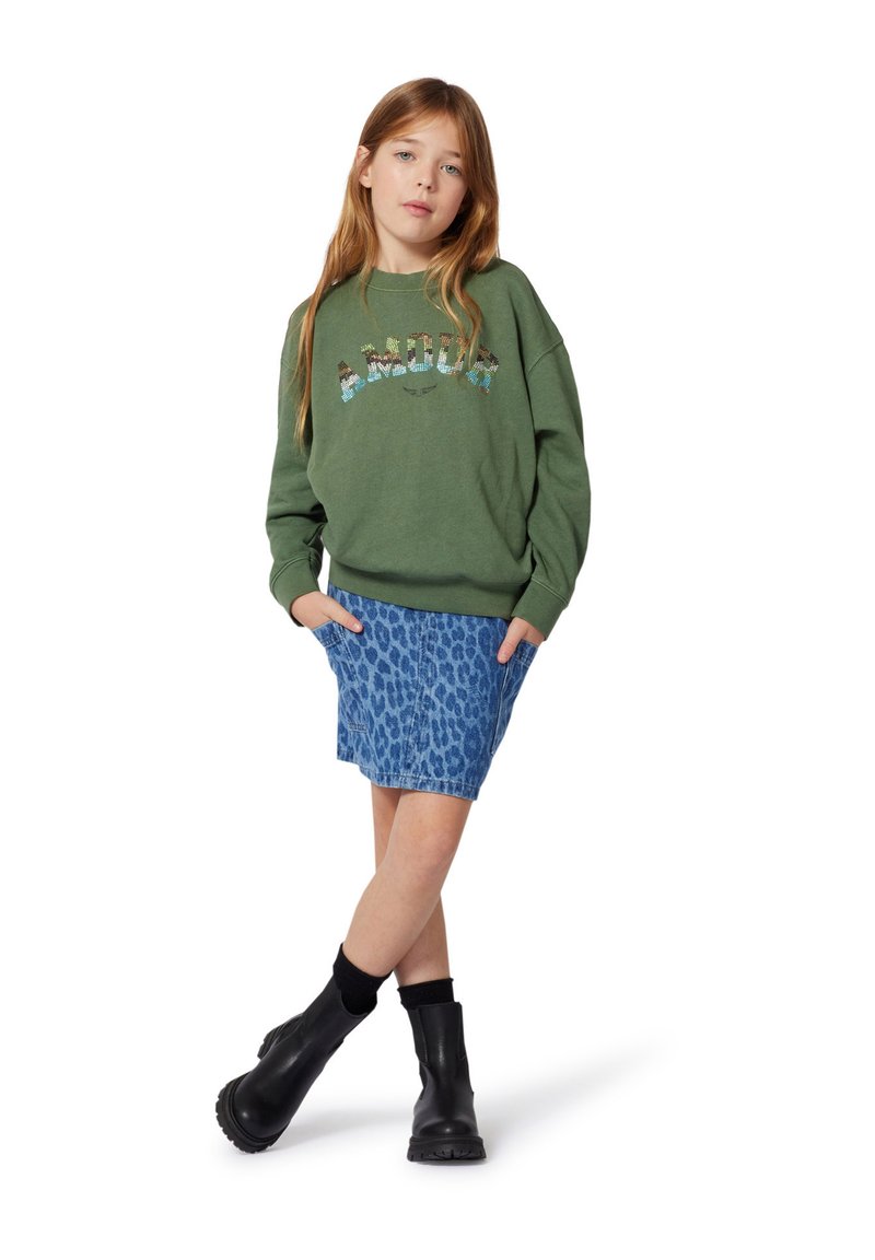 Sweatshirt en coton vert avec le texte "AMOUR", associé à une jupe en denim à imprimé léopard bleu. Des bottines noires viennent compléter la tenue.