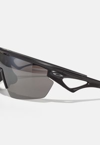 Schwarze Sportsonnenbrille mit schlankem Design, getönten grauen Gläsern und markantem, eckigem Rahmen mit Aussparungen. Leichtes Material.