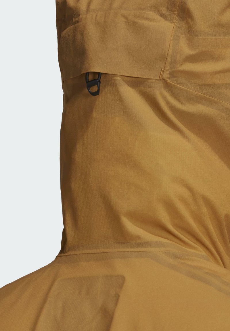 Chaqueta con capucha color caqui de textura suave, con un detalle de broche negro y una sutil costura de bolsillo, diseñada para uso al aire libre.