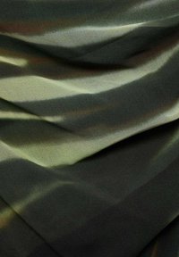 Tissu texturé en nuances de vert et de noir, présentant un motif ondulé avec des tons clairs et foncés variés, créant une apparence douce et superposée.