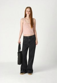 Svito roza kratka majica na naramnice, kombinirana s črnimi širokimi jeans hlačami. Videz dopolnjuje črna prešita torba in rjave platforme.