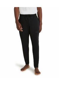 Zwarte sportbroeken met een elastische tailleband en een trekkoord. Voorzien van een slim fit en subtiele "FALKE" branding op het onderbeen.