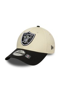 Boné bege com uma viseira preta e tira ajustável. Apresenta um logo dos Raiders bordado na frente. Textura de tecido suave.
