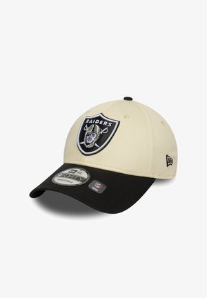 Boné bege com uma viseira preta e tira ajustável. Apresenta um logo dos Raiders bordado na frente. Textura de tecido suave.
