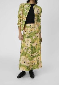 Chemise à motifs floraux et jupe assortie dans des tons de vert, jaune et rose. Les deux pièces ont une coupe décontractée, fabriquées en tissu léger.