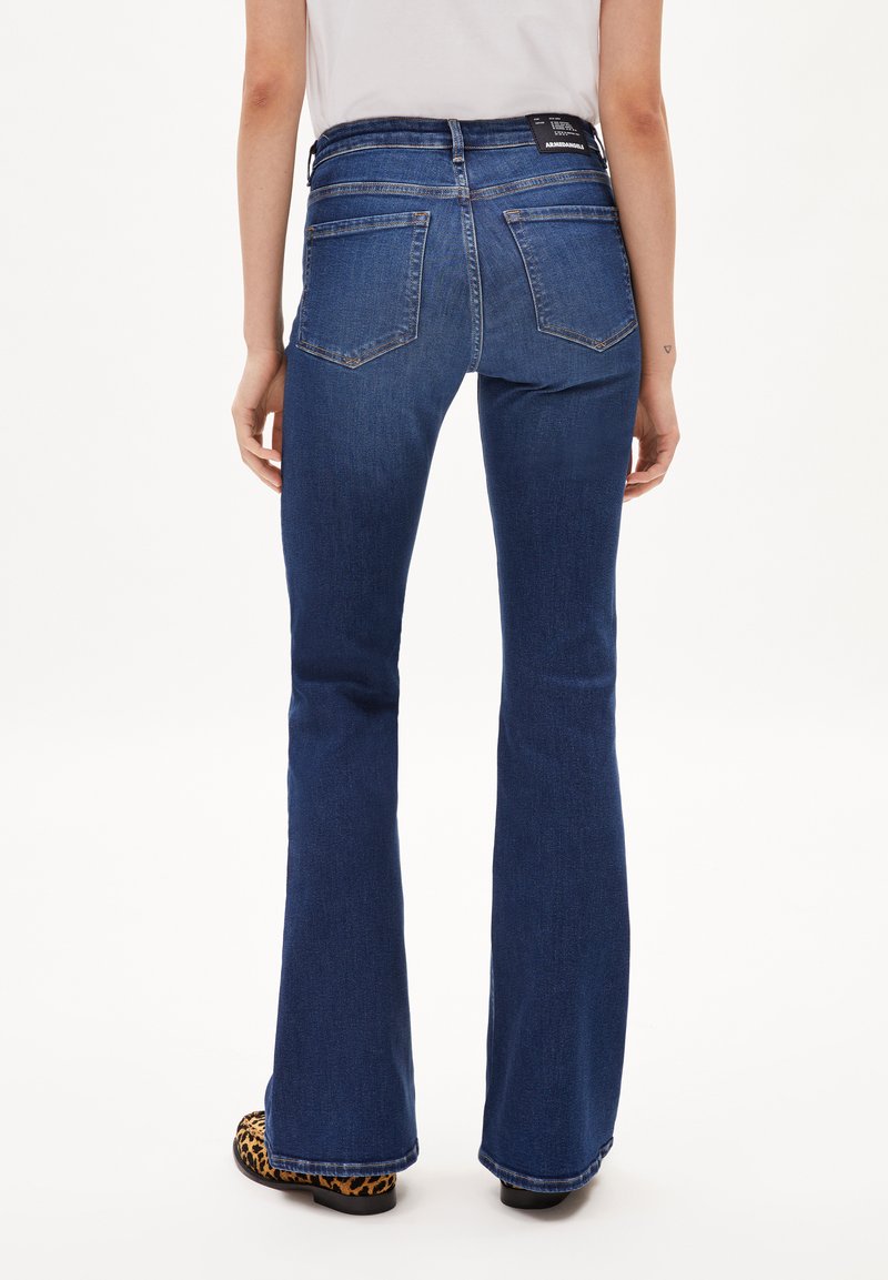 Dunkelblaue Schlagjeans aus Denim. Die Rückseite hat zwei Taschen und einen hohen Bund mit gesteppten Akzenten.