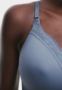 Sujetador azul claro con detalles de encaje, tirantes ajustables y textura suave. Vista en primer plano que muestra el detalle del tirante y la tela suave.