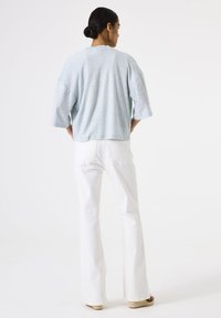 Lichtblauw oversized T-shirt met korte mouwen en een gestructureerde afwerking, gecombineerd met witte, recht gesneden jeans en tan espadrilles.