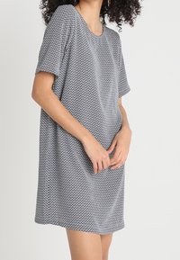 Lyhythihainen mekko mustavalkoisessa geometrisessä kuosissa, kevyttä kangasta, rento istuvuus, pyöreä pääntie ja polveen ulottuva helma.