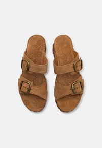 Brune semskede sandaler med to justerbare remmer og messingspænder. Den teksturerede sål har et blomstermotivet mønster.