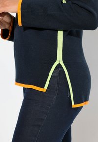 Maglione a navale con polsini e accenti laterali ribassati arancioni e verdi. Presenta spacchi laterali all'orlo per un ulteriore dettaglio di design.
