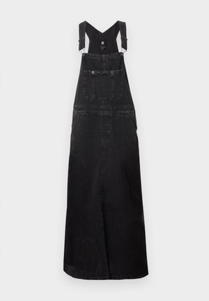 Vestido de queble em denim preto com alças ajustáveis, bolsos frontais e um corte longo e reto. Apresenta um tecido texturizado e um design simples.