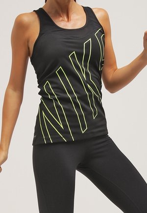 Black athletic tank top with large neon green "NIKE" lettering, featuring a scoop neckline and a fitted design. Matched with black leggings.
