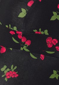 Tecido preto com um padrão de bagas e folhas em vermelho e verde, com uma textura suave e detalhes de costura visíveis.
