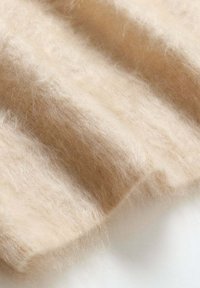 Tessuto lavorato a maglia di un beige chiaro con una texture morbida e soffice, caratterizzato da un motivo a coste e una leggera lucentezza.