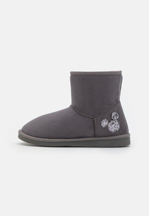 Botte d'hiver grise montant à la cheville, semelle plate, avec une décoration scintillante en forme de tête de Mickey Mouse sur le côté extérieur près du talon.