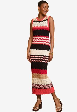 Knit maxi dress featuring a zigzag pattern in red, black, cream, and peach hues. Sleeveless design with a rounded neckline and fitted silhouette.