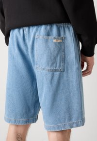 Bermuda in denim blu chiaro con vita elasticizzata, tasche laterali e tasca posteriore con patch del logo Calvin Klein.