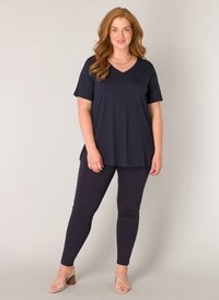 Marineblauwe v-hals t-shirt en bijpassende leggings van zachte stof. Eenvoudig ontwerp met korte mouwen, gecombineerd met lichte sandalen met bandjes.