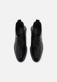 Sorte lær ankle boots med en glat overflade, snørebåndsdesign og teksturerede detaljer på overdelen. Har en løkke til nem påtagning.