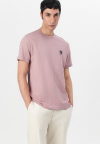 Tricou din bumbac roz deschis cu mâneci scurte și un mic patch logo rectangular pe pieptul stâng. Design ajustat cu decolteu rotund.