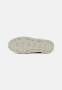 Weiße Sneaker-Sohle mit rippigem Muster, umgeben von einem kreisförmigen Rand und mit dem prägnant eingeprägten Schriftzug "CPH".