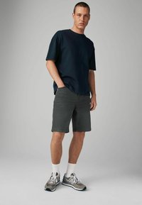 Tricou bleumarin cu mânecă scurtă, combinat cu șorturi din denim gri. Adidași gri și albaștri cu sireturi. Fit casual, design minimalistic.
