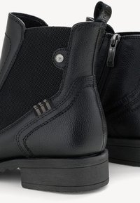Černé kotníkové boty s texturovaným koženým svrškem, síťovinovou panelem, bočním zipem a kulatou špičkou se třemi ozdobnými pruhy na podpatku.