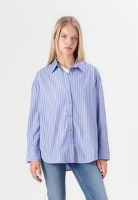 Camicia a righe blu e bianche con una vestibilità comoda, chiusura con bottoni, colletto classico e maniche con risvolto, realizzata in tessuto morbido.
