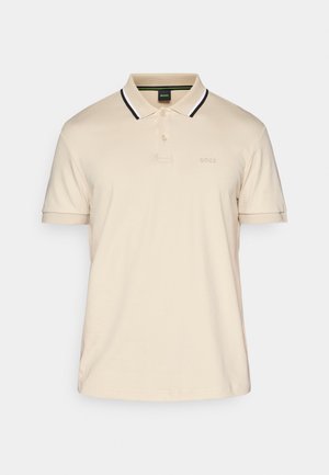Bež polo majica od pamuka, s klasičnom ovratnikom s crno-bijelim prugama, kratkim rukavima i malim logotipom na prsima.