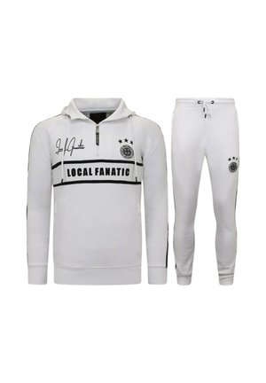 Wit trainingspak bestaande uit een pullover met een ritssluiting bij de hals en een broek. Voorzien van zwarte strepen, logo details en drie sterren op het bovenstuk.