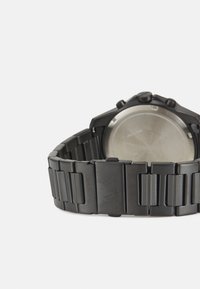 Orologio da polso in metallo nero con bracciale ampio e a maglie e cassa rotonda. Finitura opaca con loghi incisi; retro trasparente.