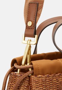 Beżowa torebka z plecionki z złotym klipsem, skórzanym paskiem i gładkim materiałowym wykończeniem, prezentująca mieszankę faktur i materiałów.