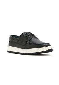 Scarpa nera in pelle con un design a profilo basso, caratterizzata da una suola in gomma bianca e lacci, pannelli testurizzati e accentuazioni laterali per una maggiore aderenza.