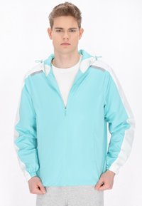 Giacca azzurra chiaro con cappuccio, dettagli bianchi sulle maniche, zip completa e polsini elasticizzati. Realizzata in un tessuto liscio e leggero.