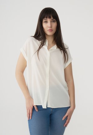 Blusa bianca a maniche corte realizzata in tessuto leggero con chiusura a bottoni davanti. Caratterizzata da una vestibilità comoda e un orlo leggermente curvo.