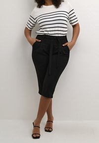 Sorte skræddersyede culottes med bånd i taljen, parret med en hvid og sort stribet t-shirt med korte ærmer. Glat tekstur, afslappet design.