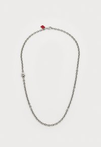 Collana in argento con maglie allungate e un elemento decorativo, con un piccolo cartellino rosso attaccato, texture liscia e finitura lucida.