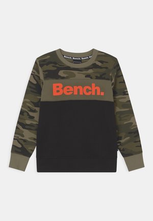 Bluza z długim rękawem z wzorem kamuflażu na rękawach i górnej części klatki piersiowej, dolna część czarna i pomarańczowe logo "Bench." z przodu.