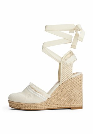 Beige Keil-Espadrillesandale mit gewebten Details, Knöchelriemchen und einem Textilobermaterial mit kleinem gesticktem Logo.