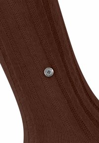 Calzature marroni con texture, dalla forma curva, con un accento in metallo argentato circolare e dettagli incisi.